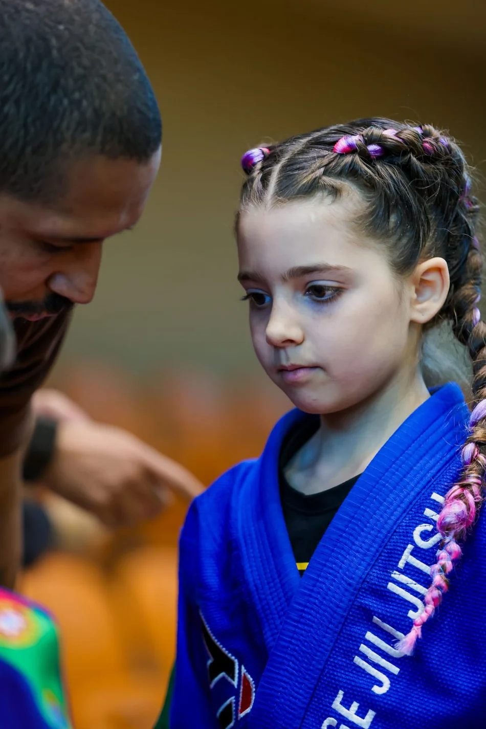 Uma praticante de kimono azul a receber orientação durante um treino publicado pela AGE